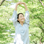 緑の木々の中で背伸びをする女性